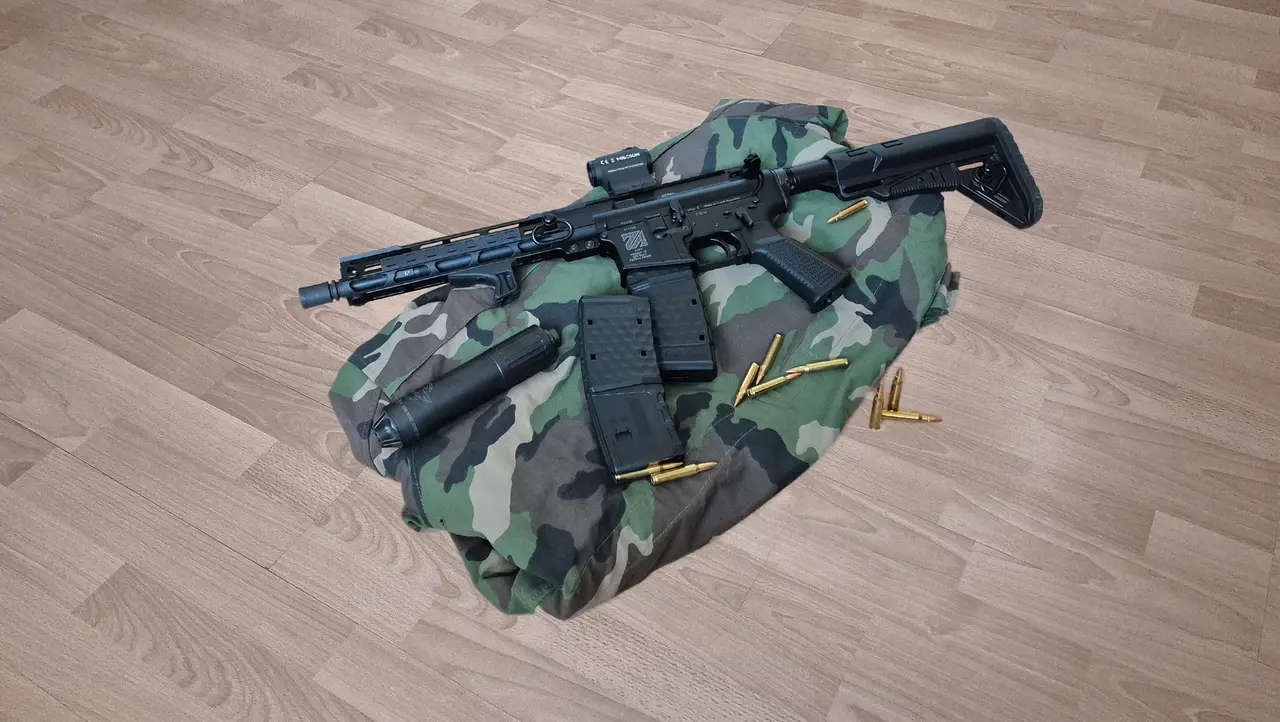 Samonabíjacia karabína AR15 s tlmičom a kolimátorom, vedľa nábojov Sellier & Bellot .223 Rem